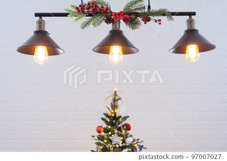 The black lampshade in the industrial loft style is decorated with spruce branches for Christmas and New Year on the background white brick wall. Close-up, minimalism 97007027