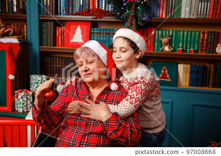 Little son and grandmother decorating Christmas tree together at home. Little son and grandmother decorating Christmas tree together at home. 97008668