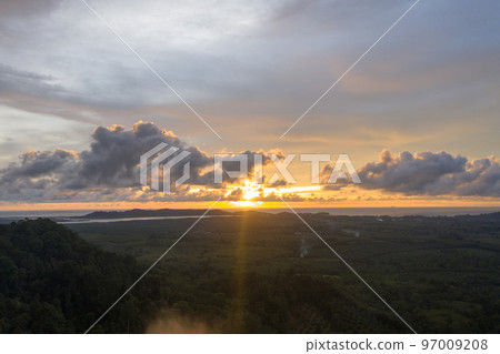 aerial view beautiful yellow sunrise above the mountain in phang Nga valley. slow floating fog blowing cover on the mountain look like as a sea of mist. scenery golden sunrise at horizon background. aerial view beautiful yellow sunrise above the mountain in phang Nga valley. slow floating fog blowing cover on the mountain look like as a sea of mist. scenery golden sunrise at horizon background. 97009208