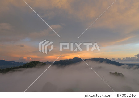 aerial view beautiful yellow sunrise above the mountain in phang Nga valley. slow floating fog blowing cover on the mountain look like as a sea of mist. scenery golden sunrise at horizon background. aerial view beautiful yellow sunrise above the mountain in phang Nga valley. slow floating fog blowing cover on the mountain look like as a sea of mist. scenery golden sunrise at horizon background. 97009210
