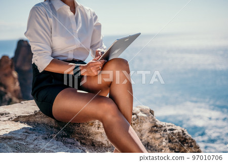 Digital nomad, Business woman working on tablet pc pad computer by the sea. Pretty lady with tablet pc on the sea, makes a business transaction online from distance. Freelance, remote work on vacation 97010706