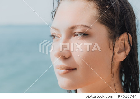 Woman sea sup. Close up portrait of beautiful young caucasian woman with black hair and freckles looking at camera and smiling. Cute woman portrait in a pink bikini posing on sup board in the sea 97010744