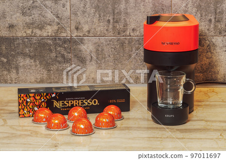Automatic Nespresso Vertuo Pop machine used to create espresso with aluminum capsules. Metal Pumpkin spice pods around Krups coffeemaker, for dripping coffee. 97011697