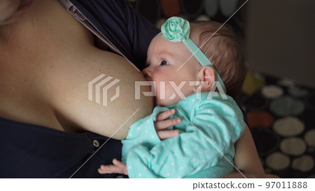 Close-up of newborn baby sucking a mother breast indoors. Childhood and family concept 97011888