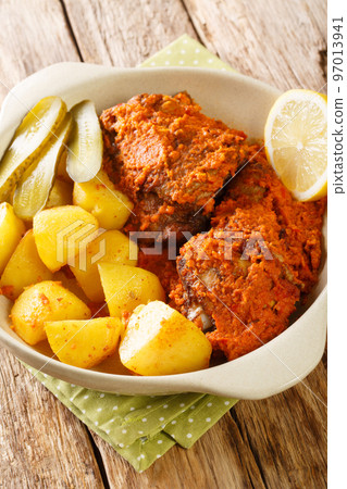 Macao fusion African chicken baked in spicy sauce with potatoes close-up in a pot on a table. Vertical 97013941