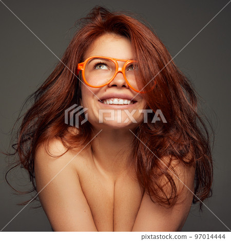 Portrait of young beautiful red-haired woman tenderly smiling isolated on dark grey background. Femininity 97014444