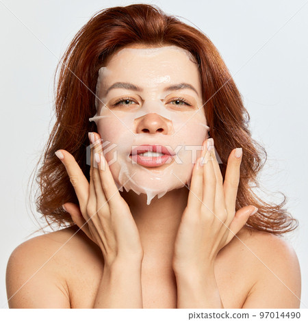 Beautiful, red-haired woman taking care after skin with moisturizing and revitalizing mask isolated on white background. Anti aging Beautiful, red-haired woman taking care after skin with moisturizing and revitalizing mask isolated on white background. Anti aging 97014490