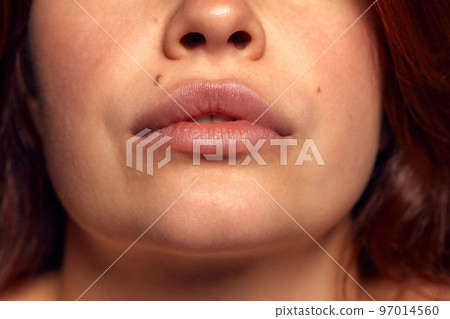Close-up view of female perfect shape mouth with nude colored lipstick. Moisturizing care. Cosmetological injections. Plump 97014560