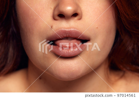 Close-up view of female perfect shape mouth with nude colored lipstick. Moisturizing care. Cosmetological lip fillers Close-up view of female perfect shape mouth with nude colored lipstick. Moisturizing care. Cosmetological lip fillers 97014561