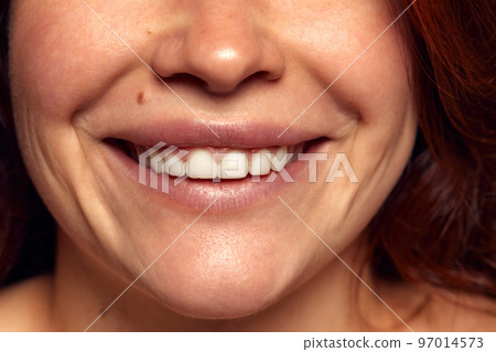 Close-up view of female perfect shape mouth with nude colored lipstick. Smiling. Cosmetological and dental care Close-up view of female perfect shape mouth with nude colored lipstick. Smiling. Cosmetological and dental care 97014573
