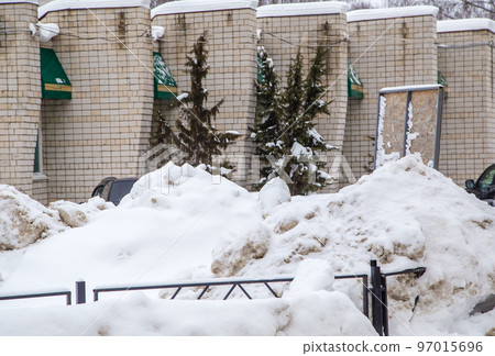 A large snowdrift against the background of a wall of a brick building. A large snowdrift against the background of a wall of a brick building. 97015696