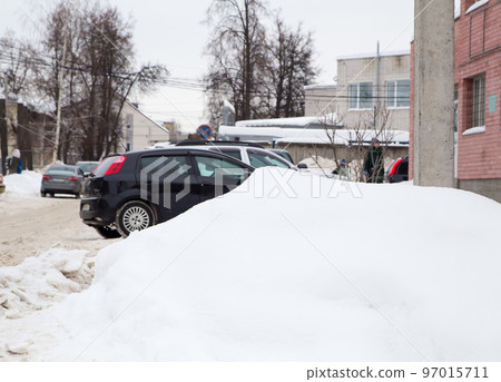 A large snowdrift on the background of a city street. A large snowdrift on the background of a city street. 97015711