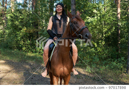 Woman in casual clothes rides a horse in early spring Woman in casual clothes rides a horse in early spring 97017898