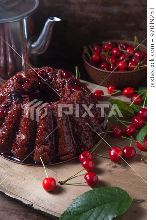 Delicious chocolate cake with sweet cherry and vintage kettle on dark wooden background.. Delicious chocolate cake with sweet cherry and vintage kettle on dark wooden background.. 97019231
