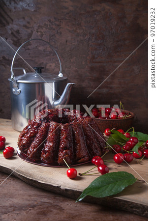 Delicious chocolate cake with sweet cherry and vintage kettle on dark wooden background.. Delicious chocolate cake with sweet cherry and vintage kettle on dark wooden background.. 97019232