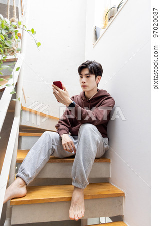 坐在樓梯上使用智能手機的人 97020087