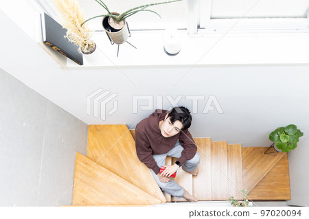Man sitting on stairs and using smartphone 97020094