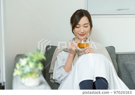 Woman sitting on sofa and drinking tea 97020163