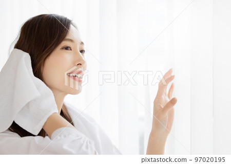 Woman wiping her hair by the window 97020195