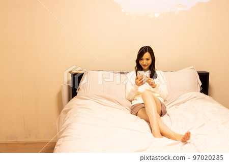 在臥室床上使用智能手機的女人 在臥室床上使用智能手機的女人 97020285