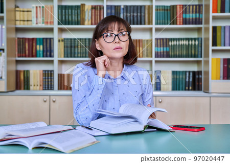 Middle aged female teacher working in library 97020447