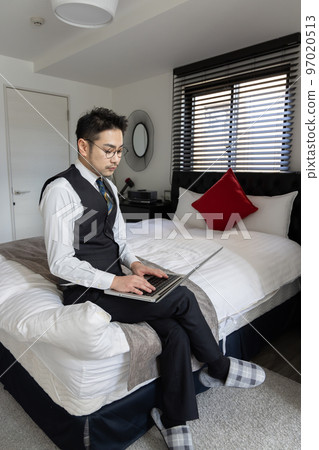 man sitting on bed using laptop man sitting on bed using laptop 97020513