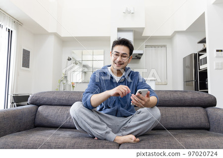 一個男人在沙發上使用智能手機 97020724