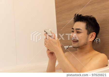 man using smartphone in bath man using smartphone in bath 97020821