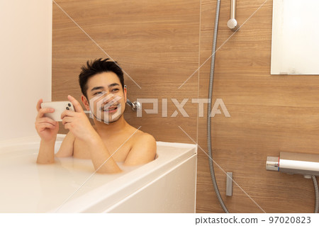 man using smartphone in bath man using smartphone in bath 97020823