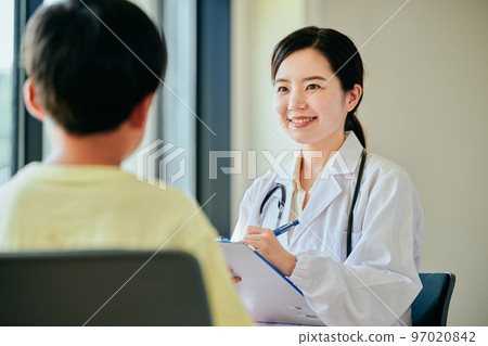 Young female doctor examining an elementary school boy Young female doctor examining an elementary school boy 97020842