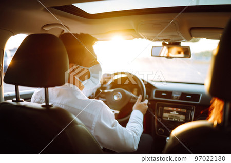 Man driving a car wearing on a medical mask during an epidemic, a driver- taxi in a mask. Covid-2019 Man driving a car wearing on a medical mask during an epidemic, a driver- taxi in a mask. Covid-2019 97022180