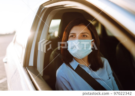 A girl and a boy driving in a car during coronavirus quarantine wearing medical masks. Safe taxi. A girl and a boy driving in a car during coronavirus quarantine wearing medical masks. Safe taxi. 97022342