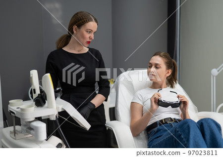 Young caucasian woman on photorejuvenation procedure. Portrait of a girl in a beautician's clinic. 97023811