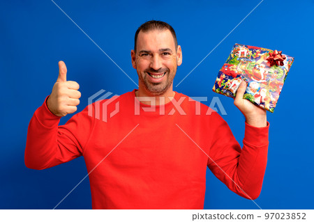 The best gift. Happy man holds a gift showing thumb up. Gift or gift box. Celebrating birthday anniversary. Special occasion. Preparation and celebration of holidays. Gift shop The best gift. Happy man holds a gift showing thumb up. Gift or gift box. Celebrating birthday anniversary. Special occasion. Preparation and celebration of holidays. Gift shop 97023852