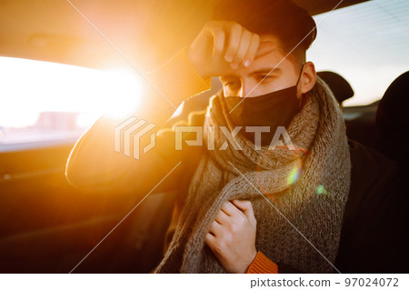 Young man in protective sterile mask in taxi car on a back seat checking her cell phone. Young man in protective sterile mask in taxi car on a back seat checking her cell phone. 97024072