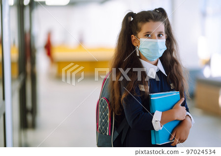 Schoolgirl in protective medical mask in school corridor when returning to school during the COVID-19. 97024534