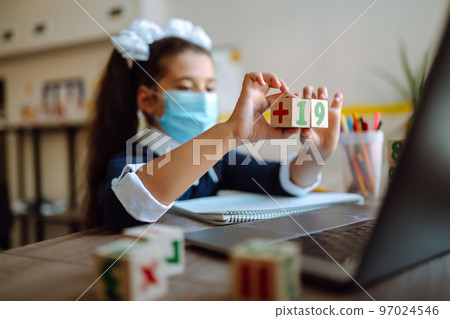 School girl in medical mask using laptop computer studying through online e-learning system. School girl in medical mask using laptop computer studying through online e-learning system. 97024546