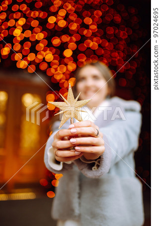 Young woman posing by the christmas tree at winter holidays. Light decorations in the streets. Young woman posing by the christmas tree at winter holidays. Light decorations in the streets. 97024695