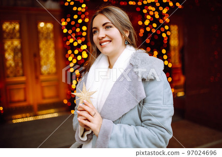 Smiling woman in winter style clothes posing at festive street market. Young woman enjoying winter moments. Smiling woman in winter style clothes posing at festive street market. Young woman enjoying winter moments. 97024696