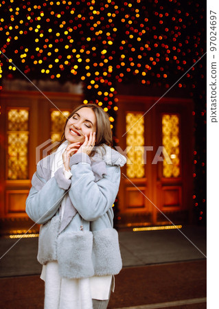 Smiling woman in winter style clothes posing at festive street market. Young woman enjoying winter moments. Smiling woman in winter style clothes posing at festive street market. Young woman enjoying winter moments. 97024697