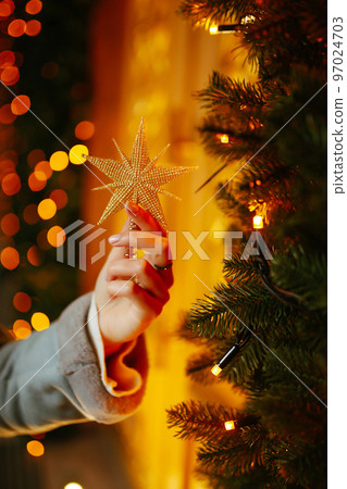 Young woman posing by the christmas tree at winter holidays. Light decorations in the streets. 97024703