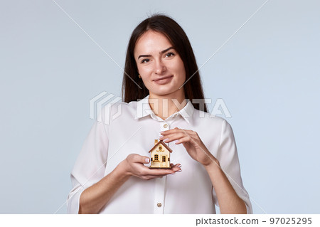 beautiful woman holding little house on gray background. 97025295