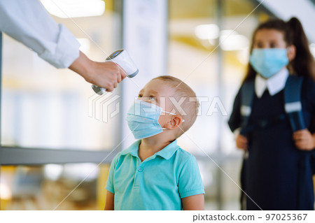 Nurse or doctor checks children body temperature using infrared forehead thermometer for virus. 97025367