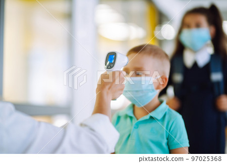 Nurse or doctor checks children body temperature using infrared forehead thermometer for virus. Nurse or doctor checks children body temperature using infrared forehead thermometer for virus. 97025368