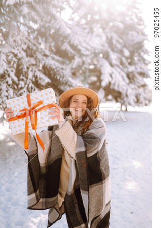 Pretty Woman holding a giftbox with red ribbon in the winter park. Happy winter time. New year's. Pretty Woman holding a giftbox with red ribbon in the winter park. Happy winter time. New year's. 97025455
