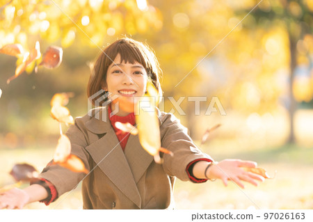 Young woman throwing fallen leaves 97026163