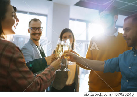 Clinking glasses with champagne. Happy coworkers celebrating their business achievement. 97026240