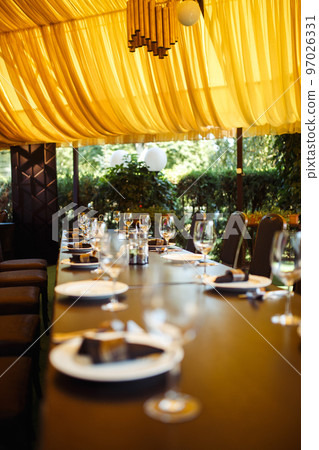 Sparkling glassware stands on long table prepared for wedding dinner. Sparkling glassware stands on long table prepared for wedding dinner. 97026331