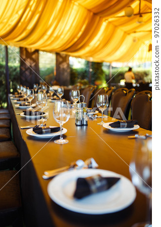Sparkling glassware stands on long table prepared for wedding dinner. Sparkling glassware stands on long table prepared for wedding dinner. 97026332