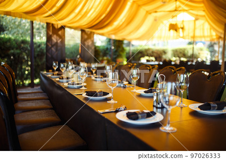 Sparkling glassware stands on long table prepared for wedding dinner. Sparkling glassware stands on long table prepared for wedding dinner. 97026333